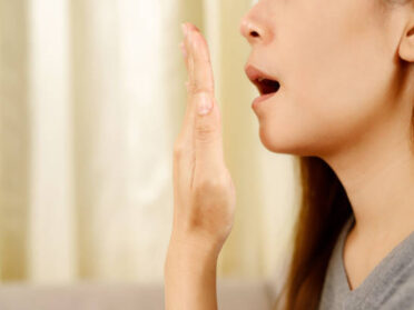 Women with bad breath can be an early sign of gum health problems. 口臭をチェックする女性